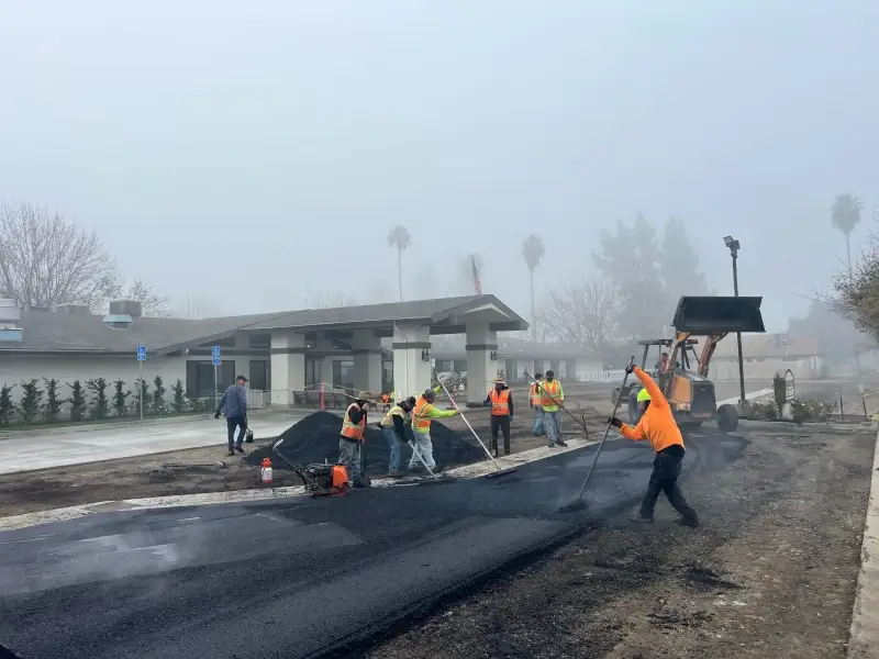 Workers installing asphalt in parking lot. 